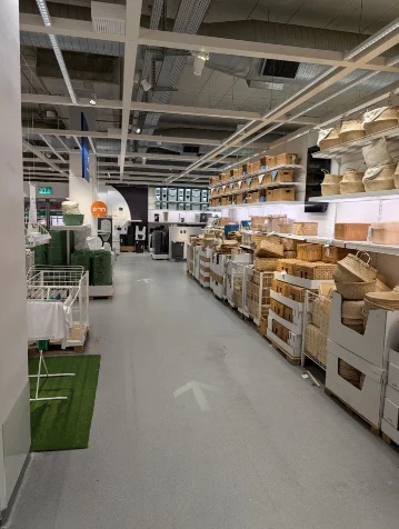 Portrait photo of the department aisle with the floor wayfinding arrow — laundry baskets left, woven baskets right
